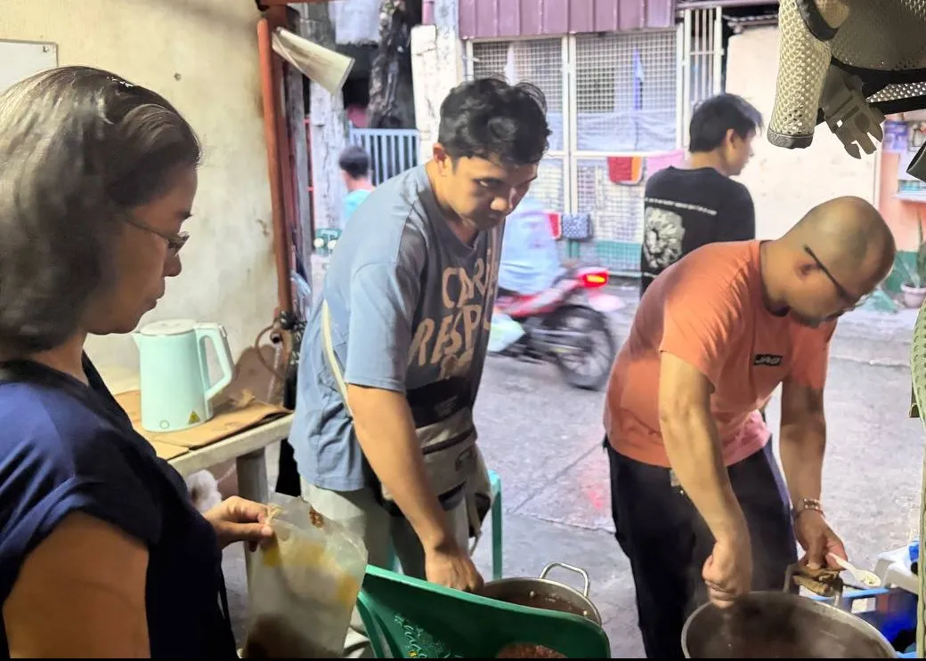 Volunteers prepare meals in large cooking pots.
